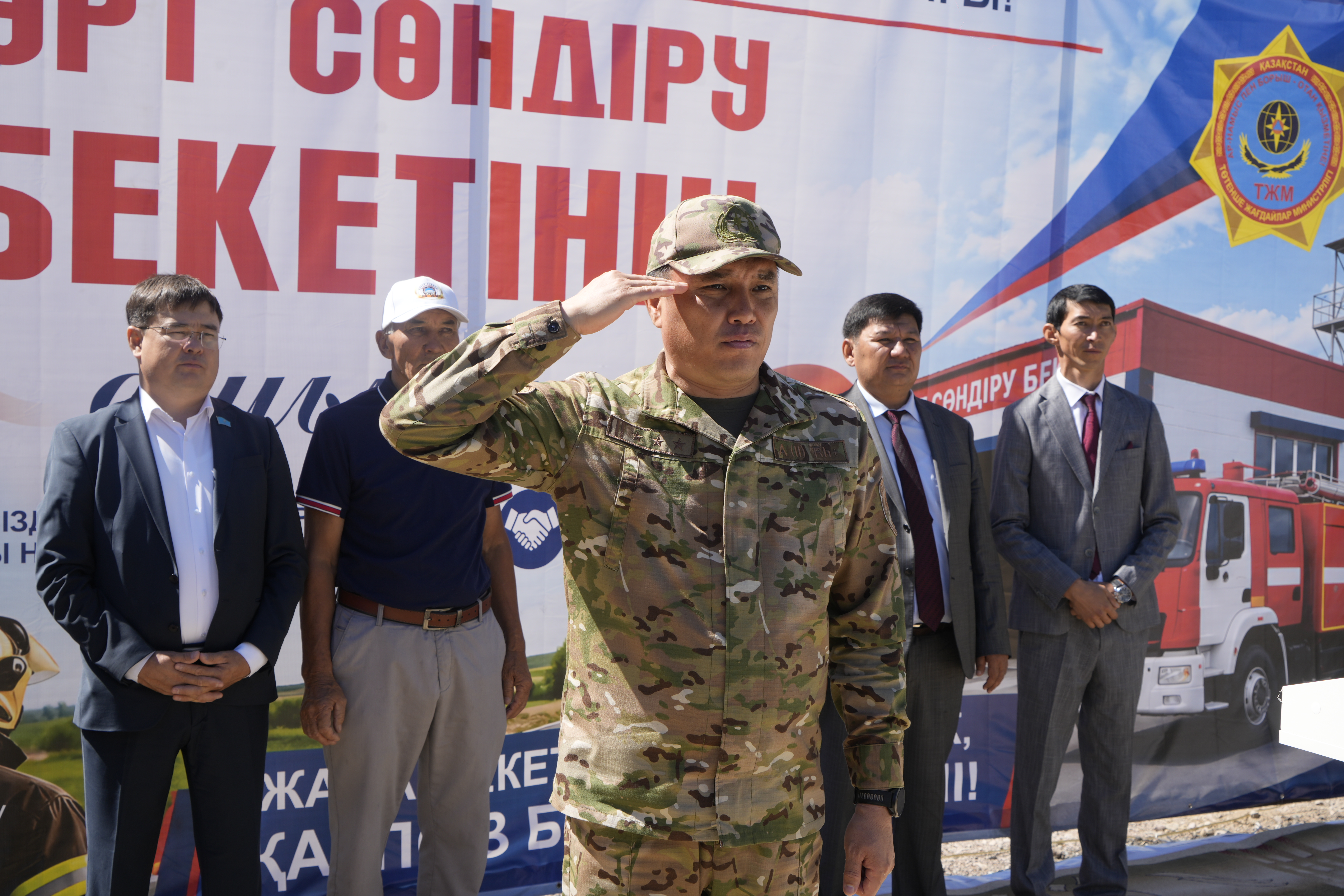 Әскери формадағы офицердің сәлем беруі және оның жанында тұрған ресми киінген ерлер.