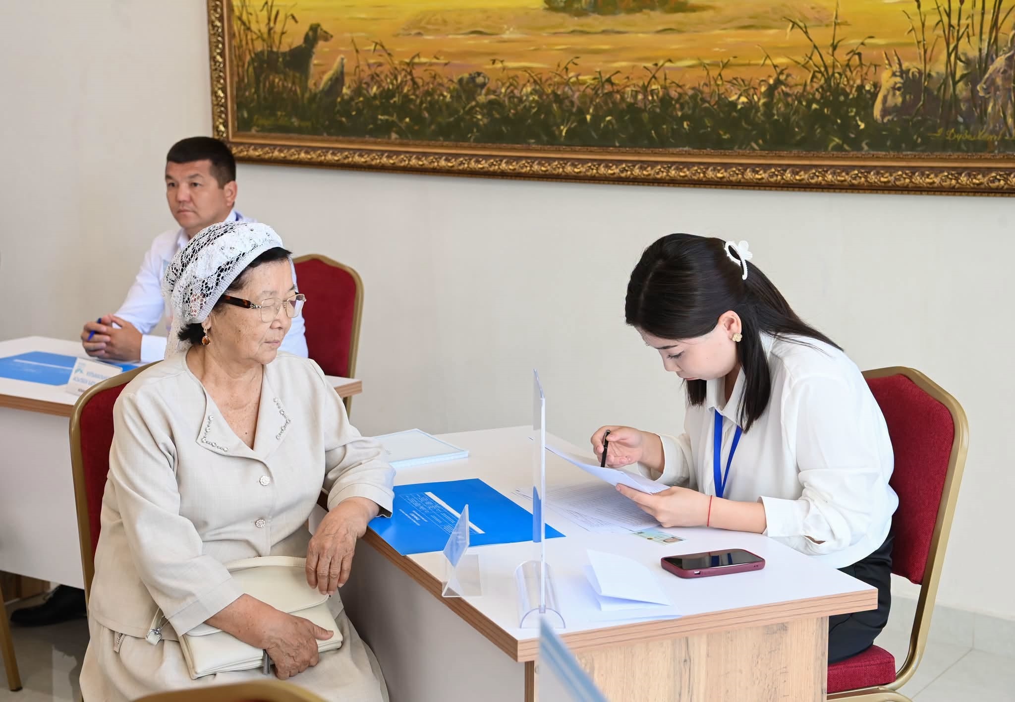 Кеңседе қызметкердің қабылдауында отырған қарт әйел.