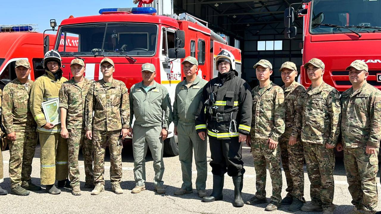Өрт сөндіру көліктерінің алдында тұрған әскерилер мен өрт сөндірушілер тобы.