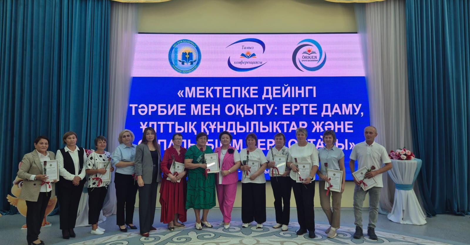 Мектепке дейінгі тәрбие мен оқыту тақырыбындағы конференция қатысушыларының сертификаттармен бірге түсірілген суреті.