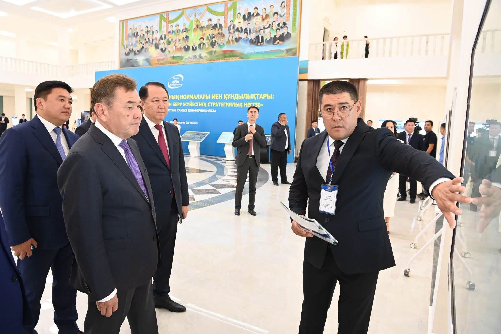 Костюм киген ер адамдар тобы көрмедегі стендті қарап тұр.