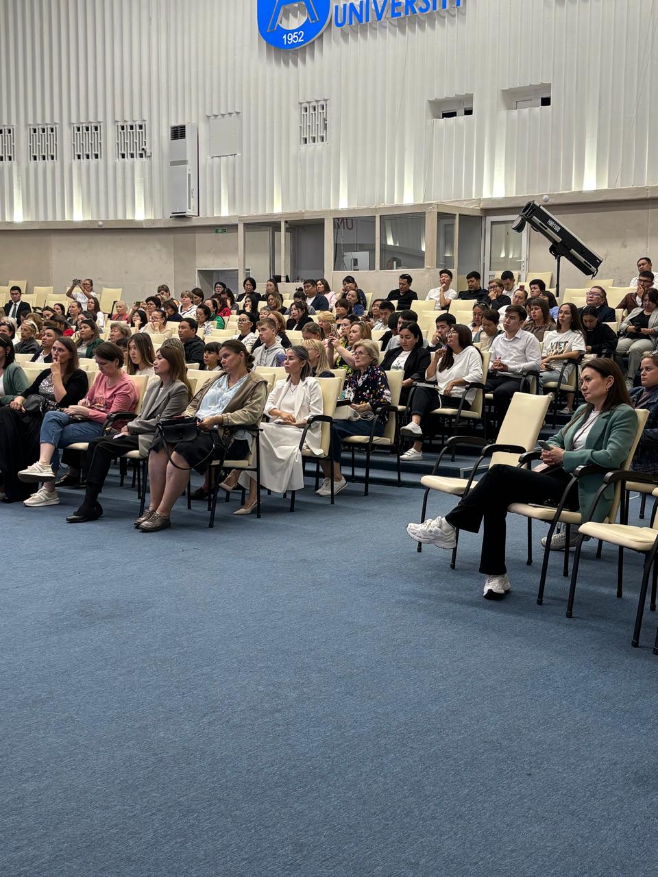 Суретте салық заңнамасының өзекті мәселелеріне арналған іскерлік семинар бейнеленген. Іс-шараның атмосферасы ресми әрі іскерлік сипатта. Қатысушылар кәсіби мәселелерді талқылап, пікір алмасуда.
